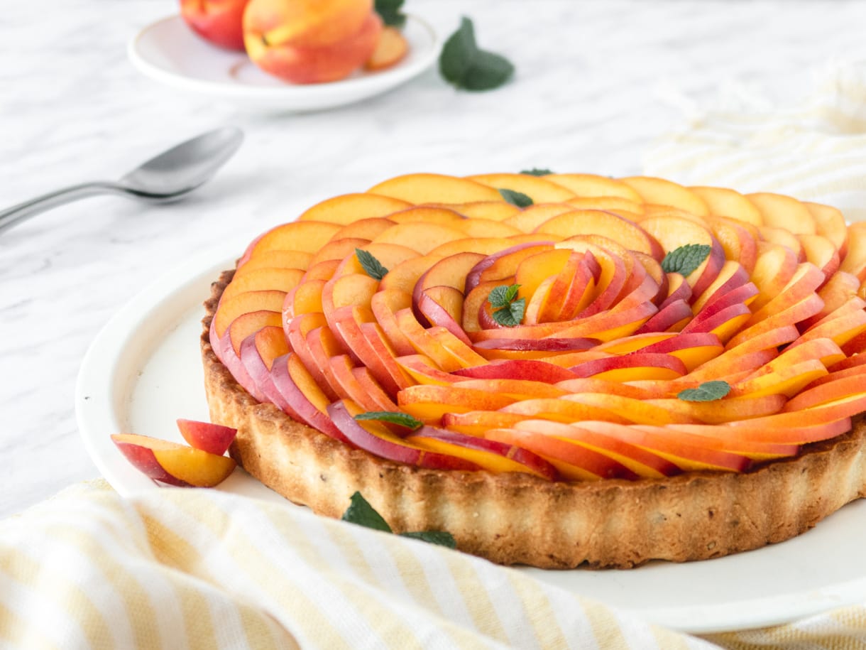 side view of a vegan nectarine tart with neactarines in the background