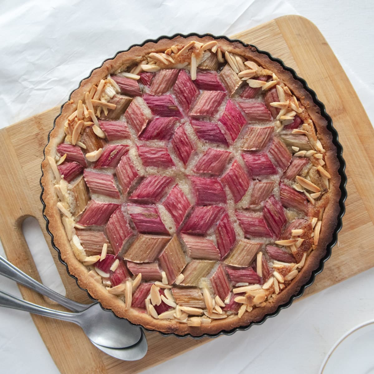 geometric rhubarb tart placed on a cutting board with some spoons