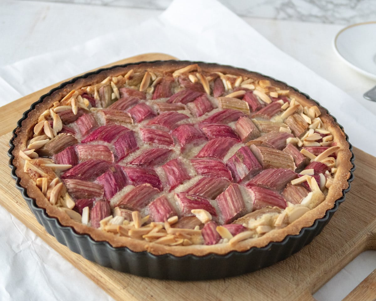 side view of a cooked rhubarb and frangipane tart on a cutting board