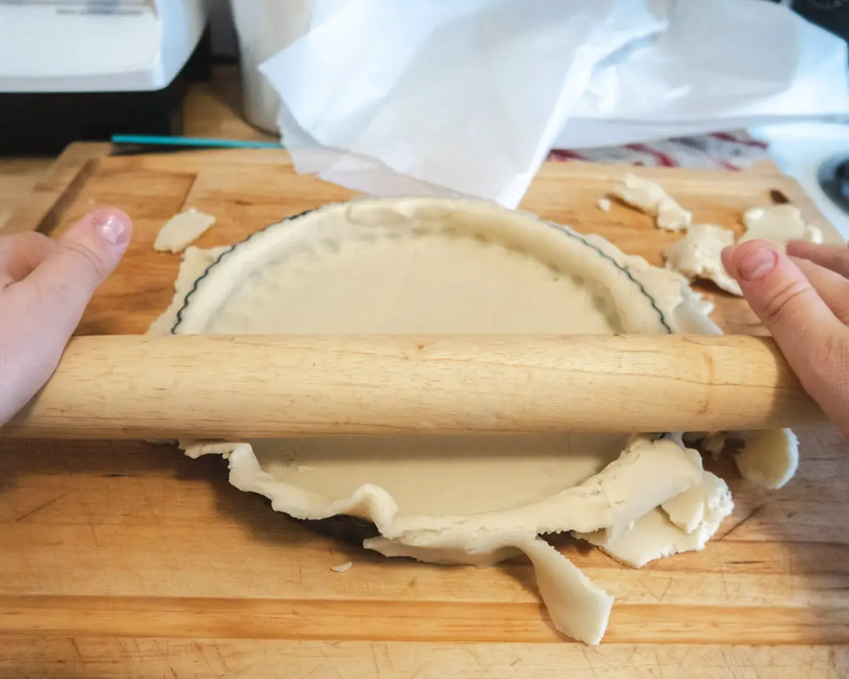 cutting the excess of dough from a tart pan with a rolling pin