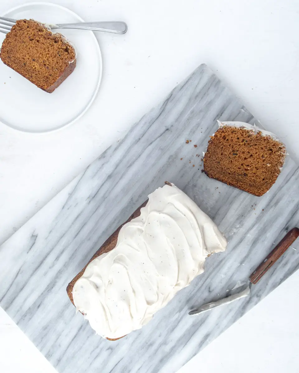 Top down view on a half-sliced pumpkin bread on a marble plate
