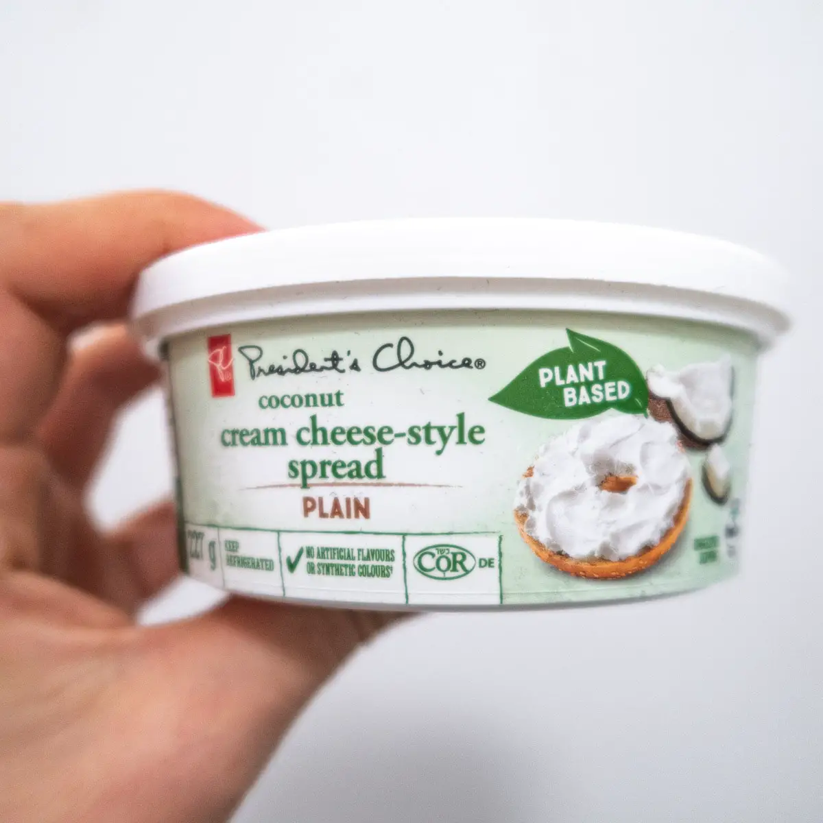 President's Choice vegan cream cheese held in front of a white background
