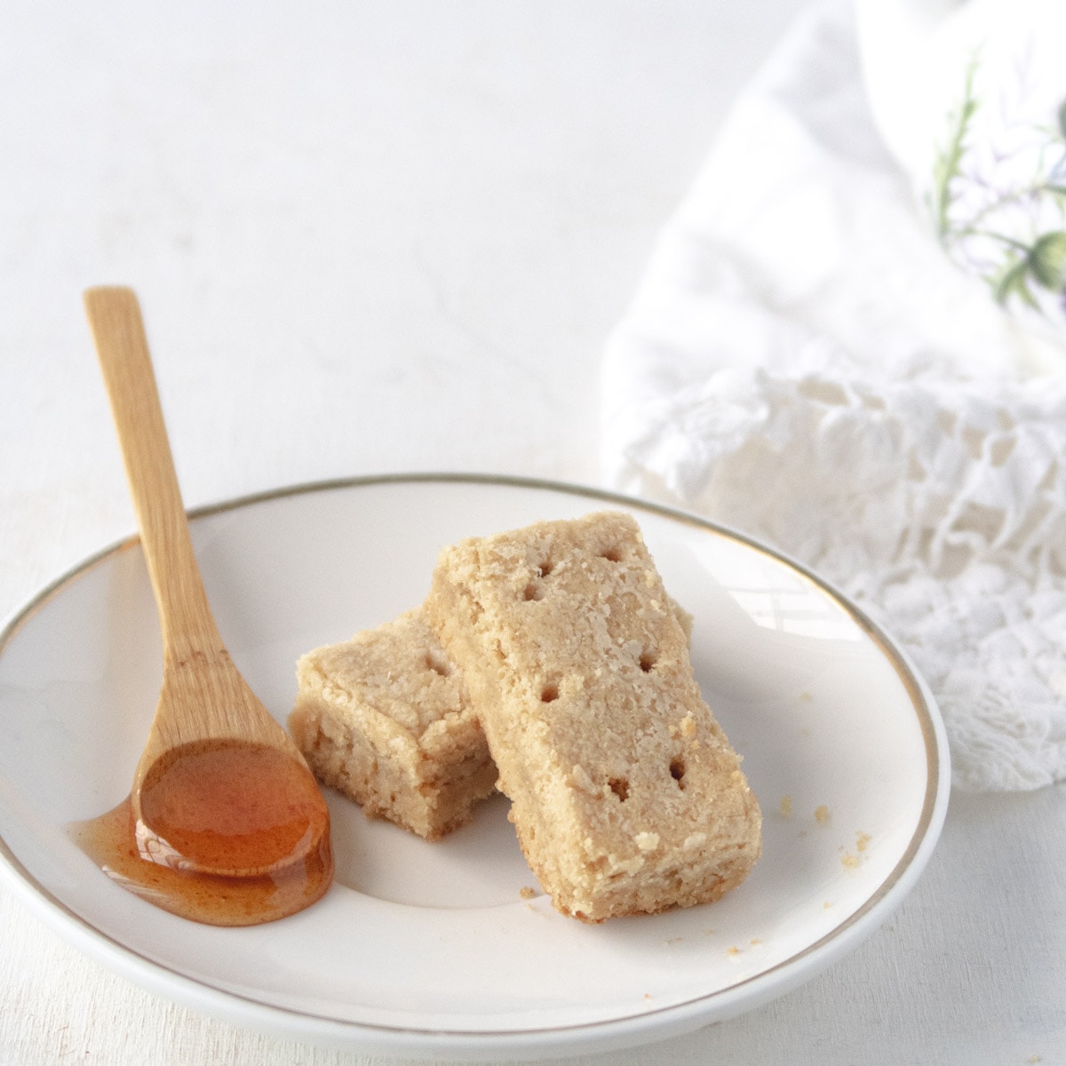 a spoon full of vegan honee on a plate with some shortbreads