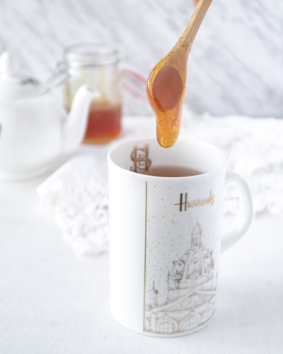 a spoonfull of vegan honey being dropped in a cup of tea