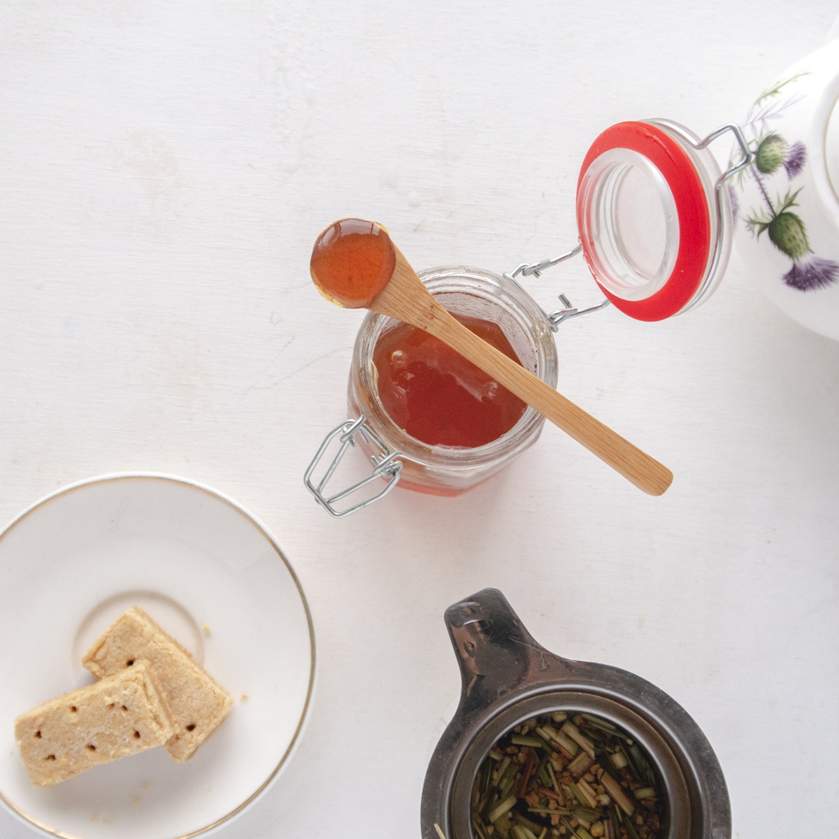 flatlay of a jar of honey, some shortbreads and some tea