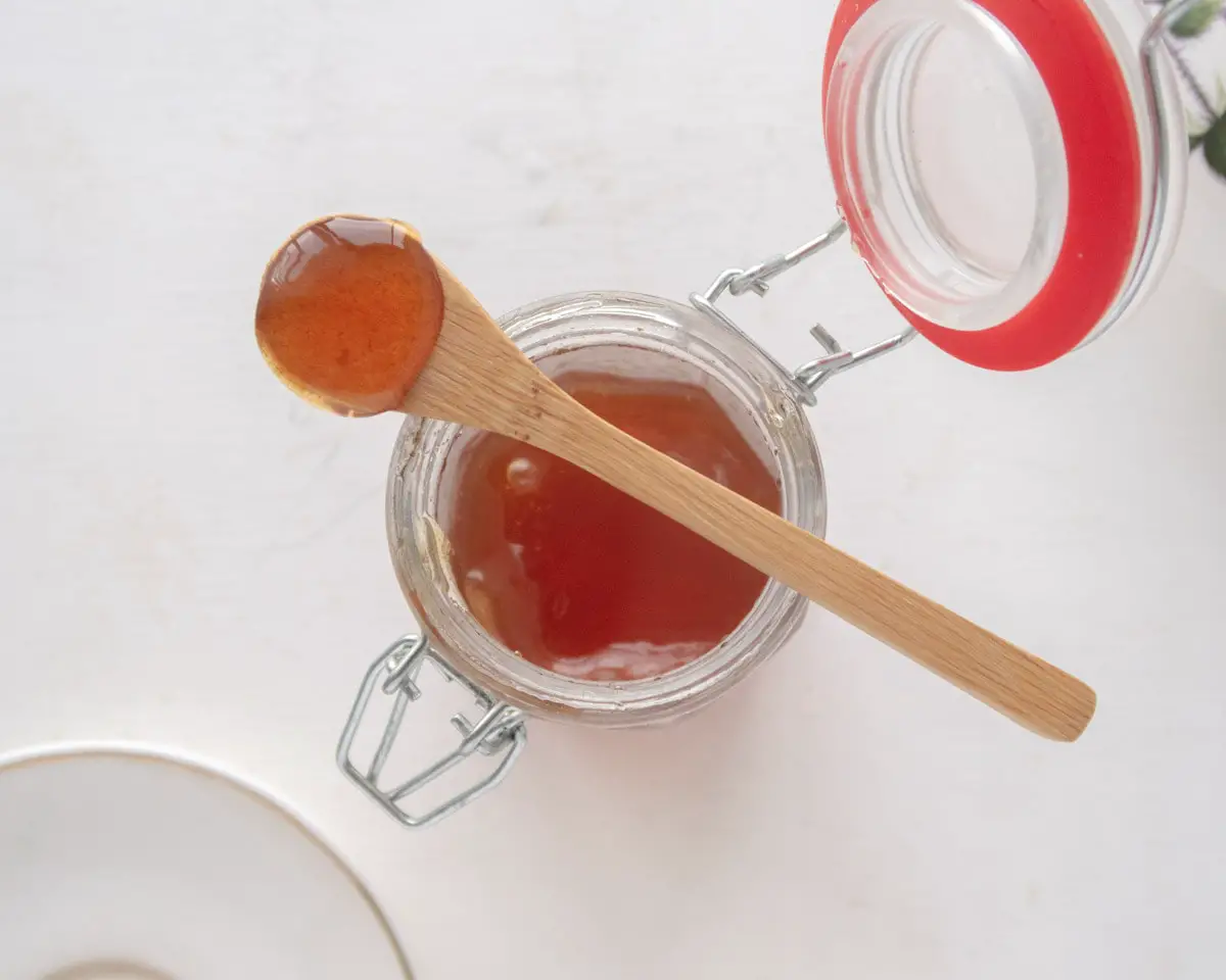 bamboo spoon laying on top of a jar of vegan honee