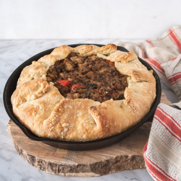curried chickpea pie in a cast-iron skillet on top of a slice of wood
