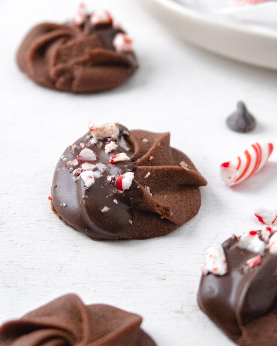 chocolate butter cookies halfway dipped in chocolate with crushed candy cane sprinkled on top