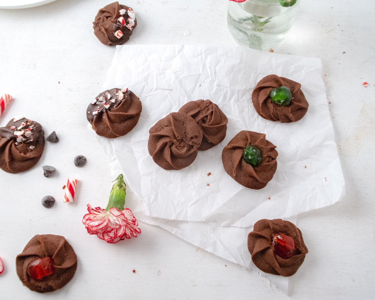 chocolate Danish cookies places randomly on a white table with some crinkled parchment paper