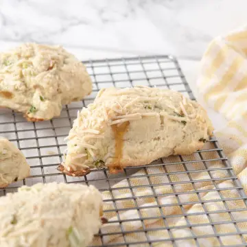 vegan herb and cheddar savoury scones on a wire cooling rack with a yellow-stripped dishtowel