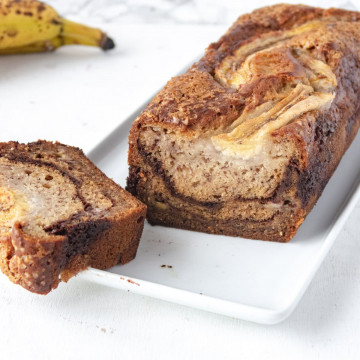 vegan banana loaf bread closeup on a plate with a slice on the side