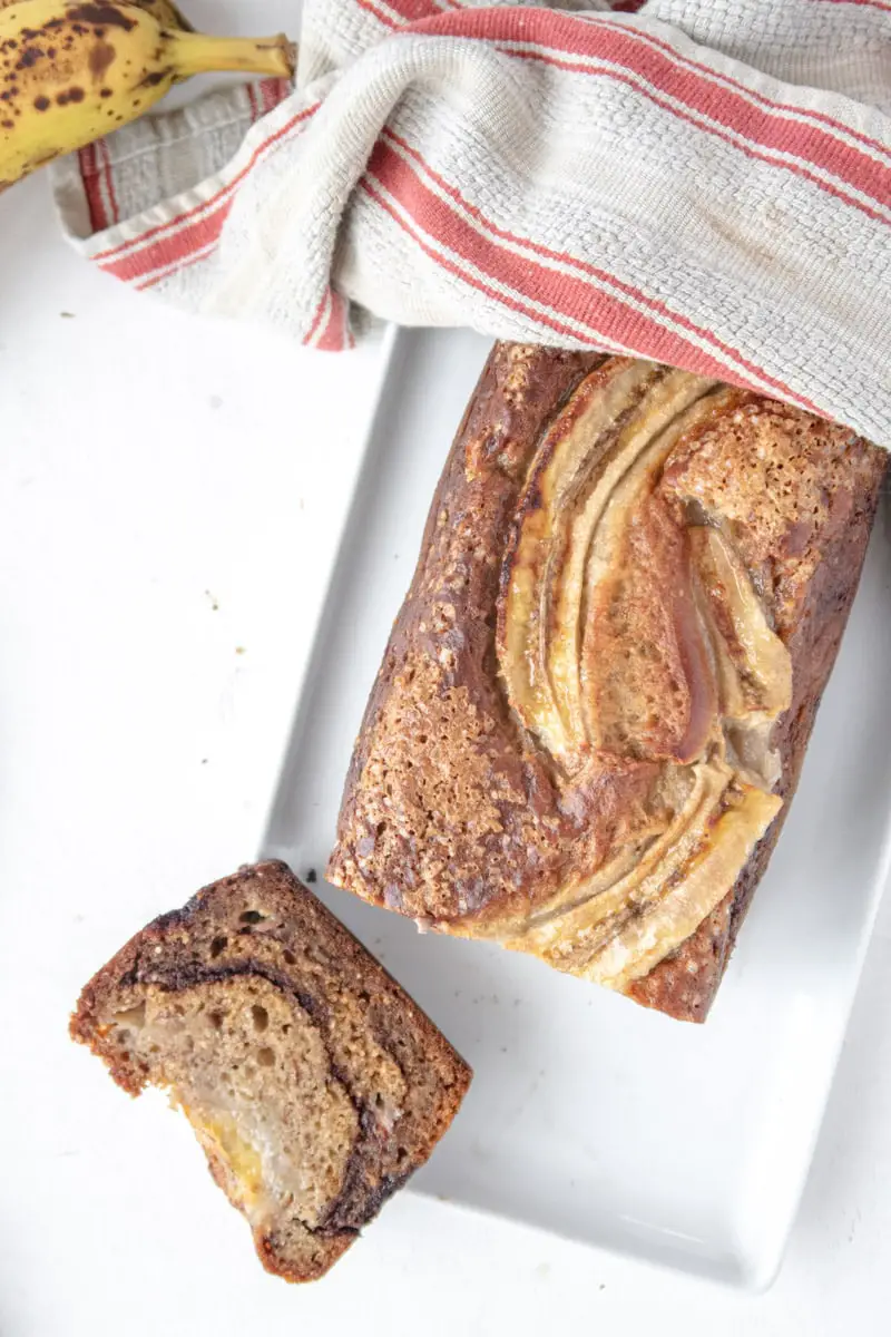 top view on a banana loaf cake on a plate with a slice on its side