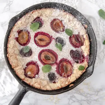 Top down view of a plum clafoutis in a cast iron skillet