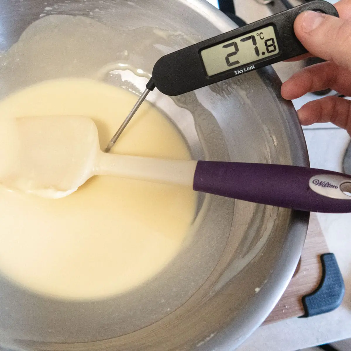 a bowl of white chocolate being checked in temperature with a digital thermometer