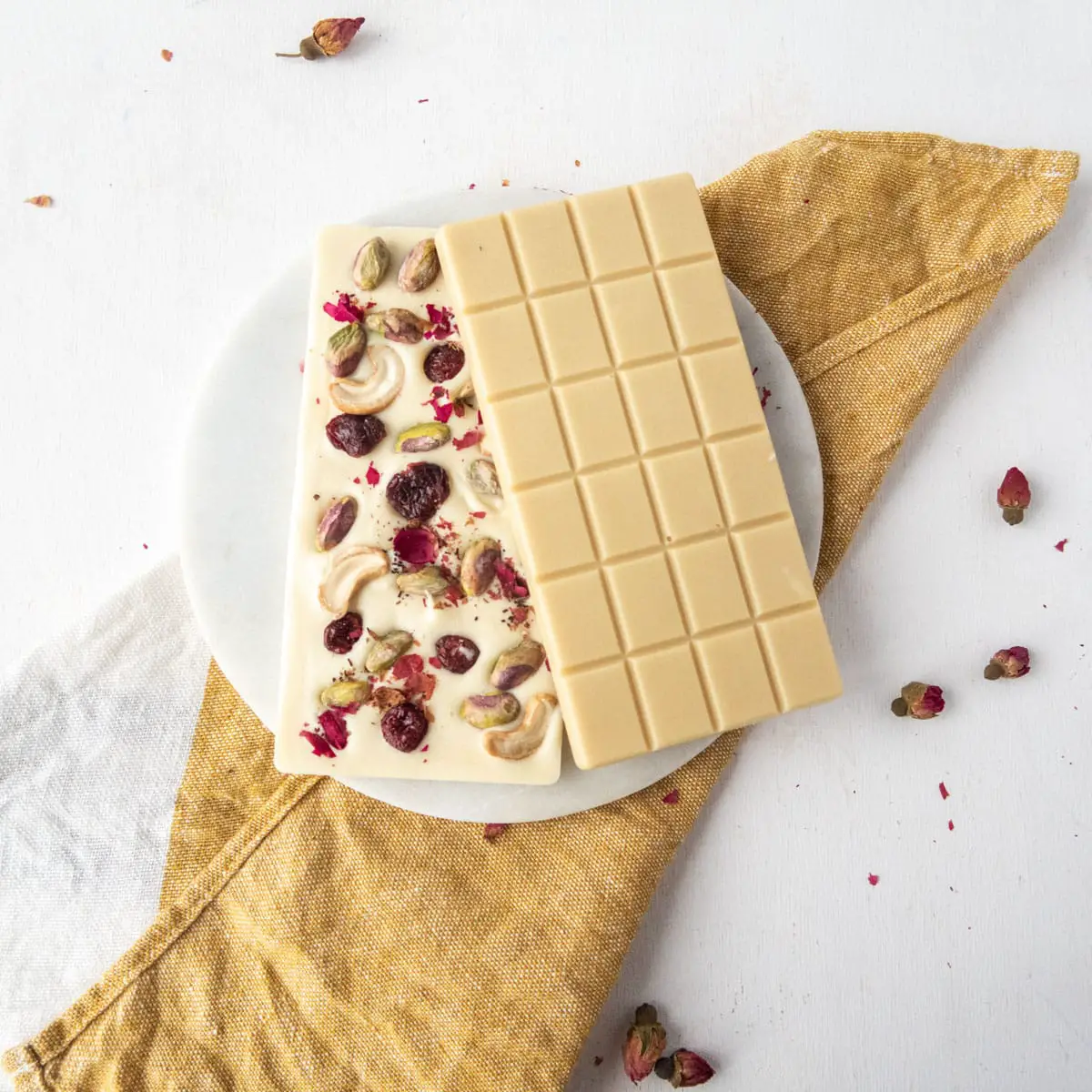 two vegan white chocolate bars on a white plate and mustard-coloured towel