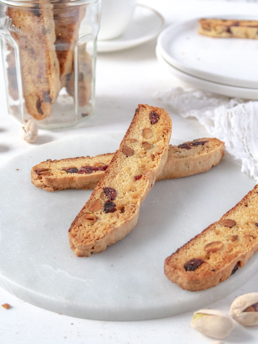 two biscottis leaning on each otehr on a marble plate with mnore biscotti in the background