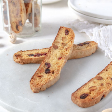 two biscottis leaning on each otehr on a marble plate with mnore biscotti in the background