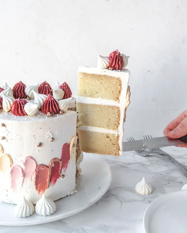 a slice of vegan vanilla cake being lifted from the rest of the cake