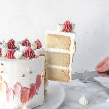 a slice of vegan vanilla cake being lifted from the rest of the cake