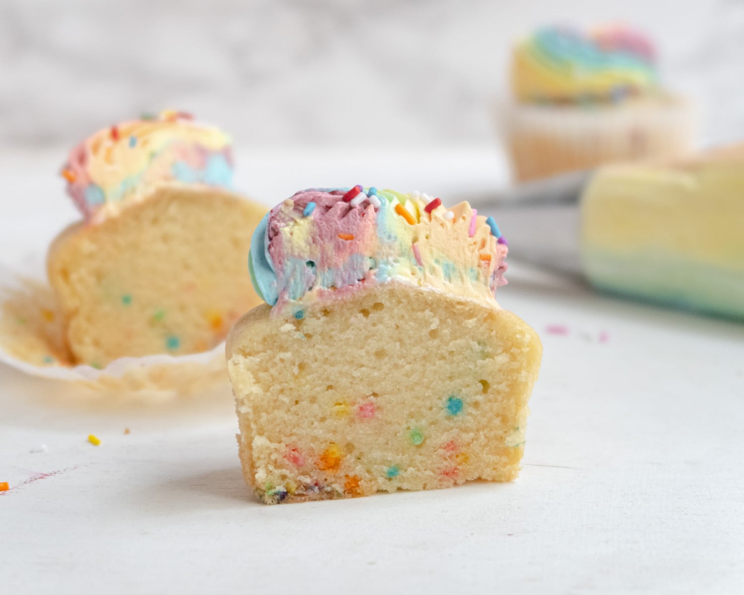 cupcake cut in half with a piping bag in the background