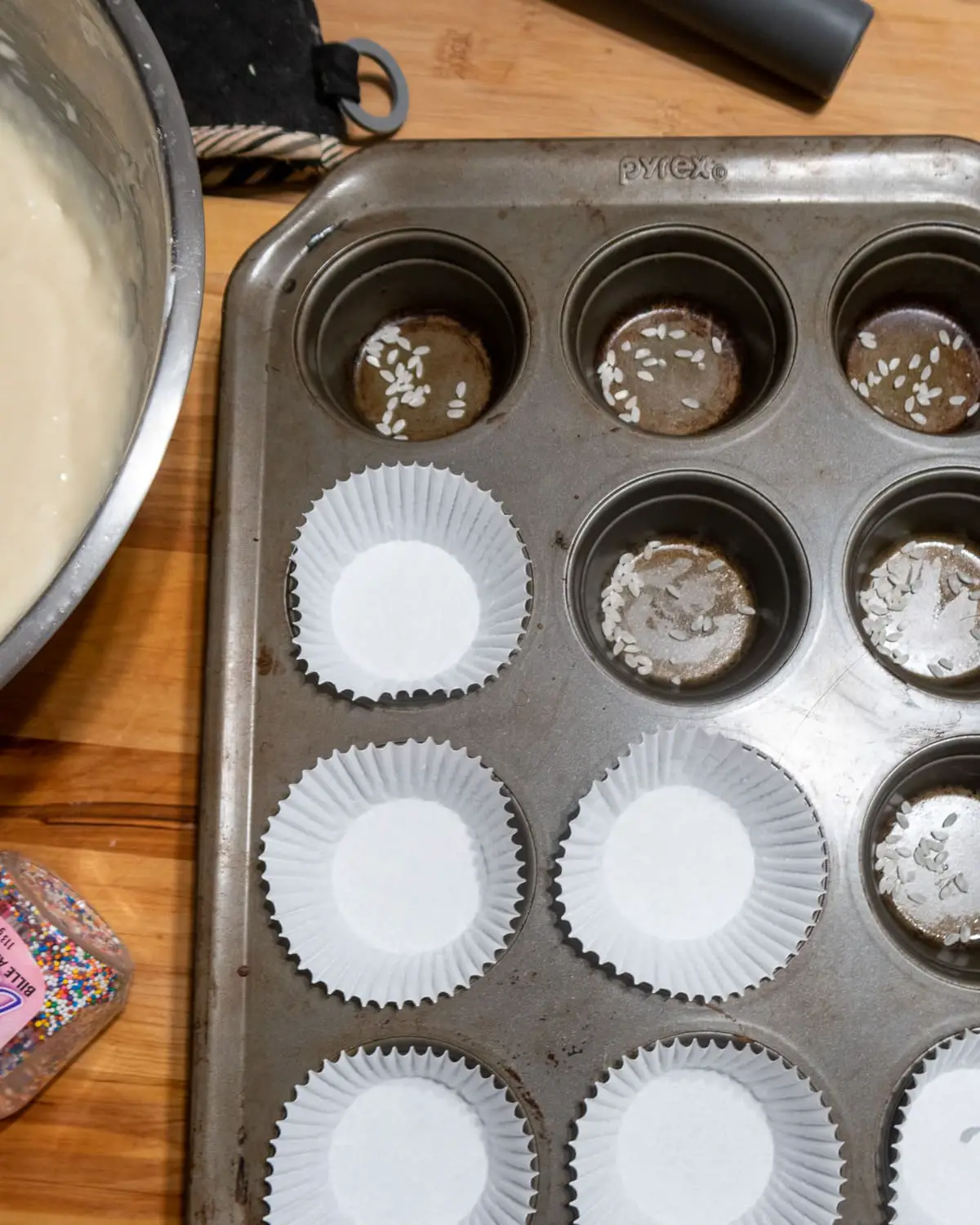 a cupcake pan with grains or rice in some cavities  and white cupcake liners in others