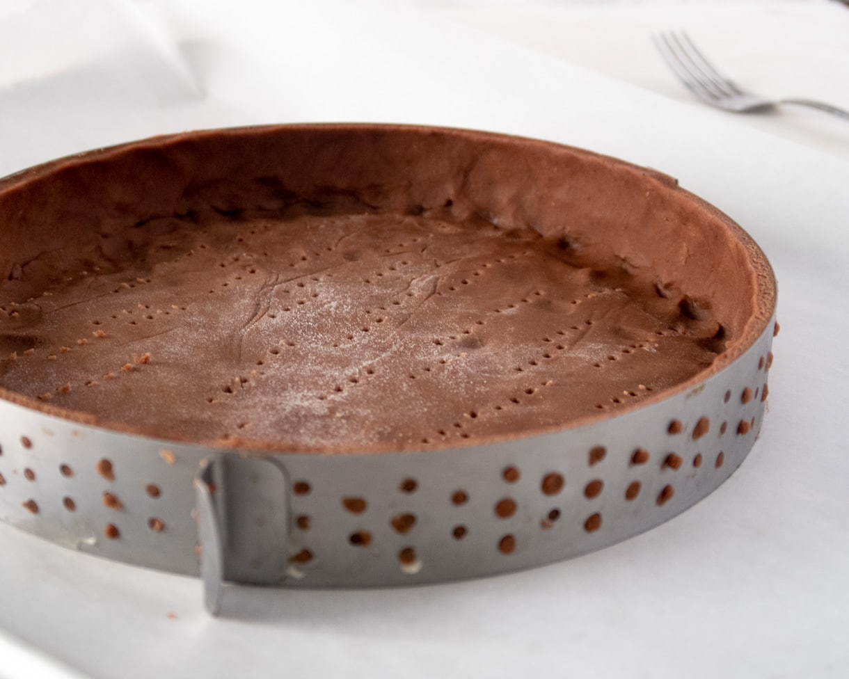 unbaked chocolate shortcrust dough in a tart ring