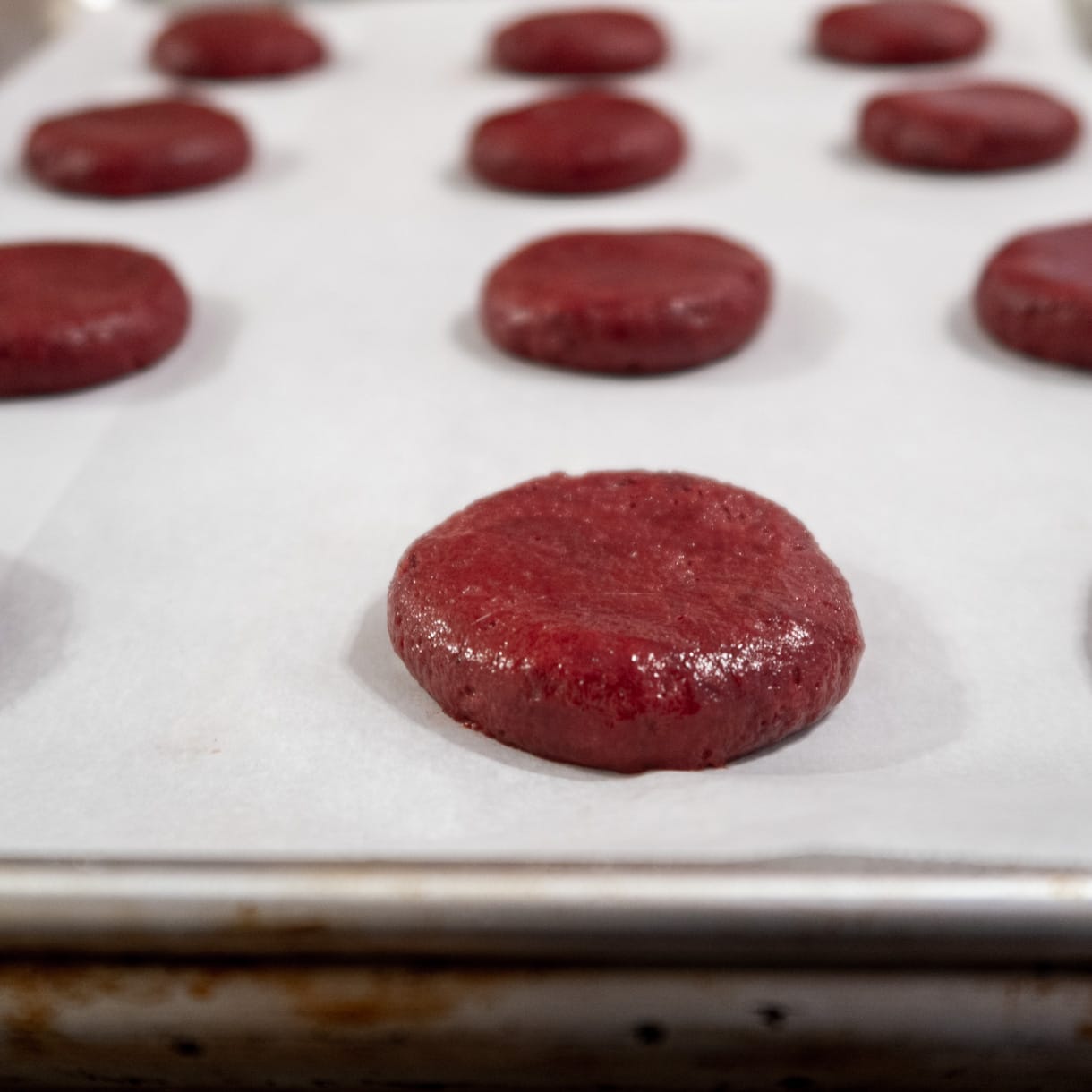 Unbaked cookies slightly flattened on a baking sheet.