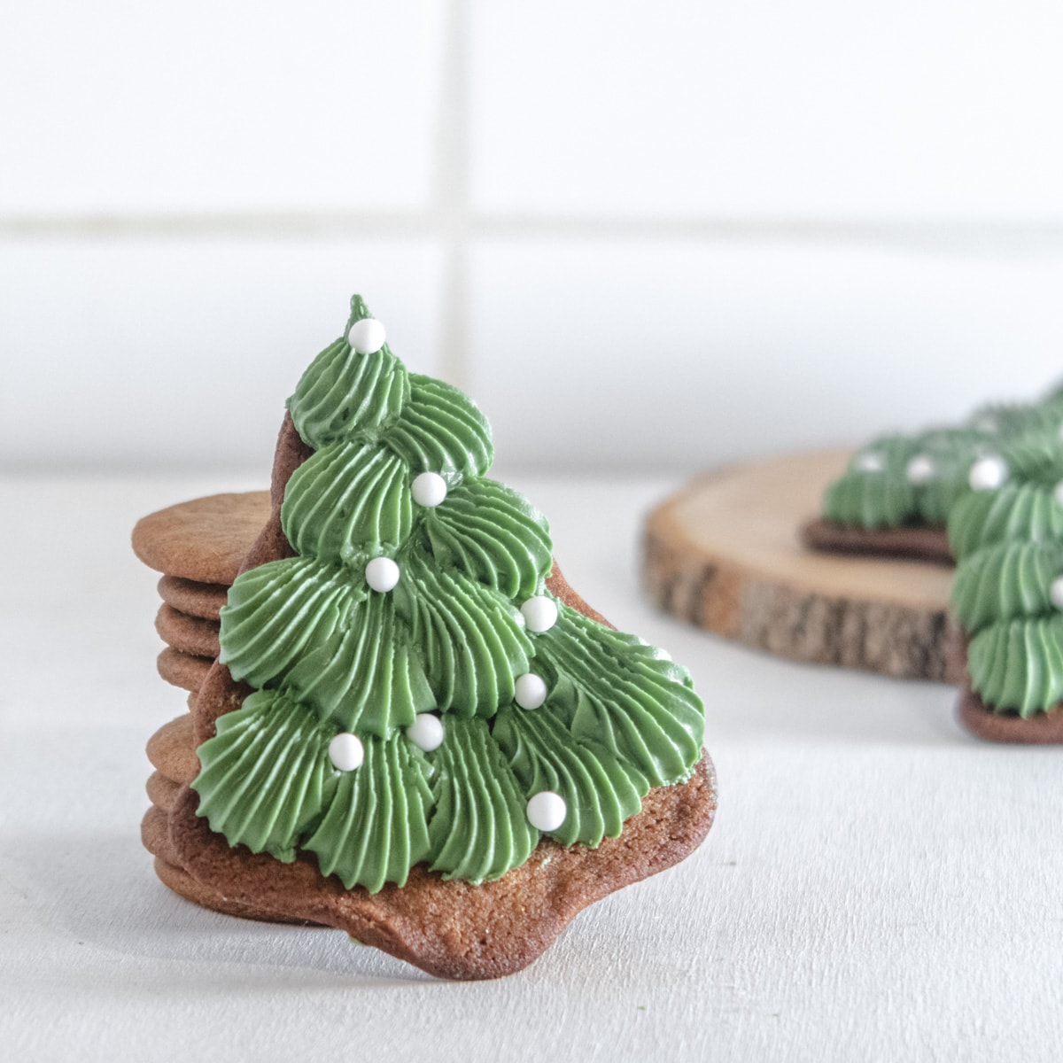 a decorate christmas tree cookie leaning against a tower of gingerbread cookies