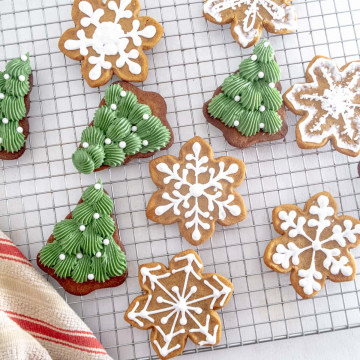 Christmas tree and snow flake vegan gingerbread cookies decorated with vegan royal icing on a wire drying rack