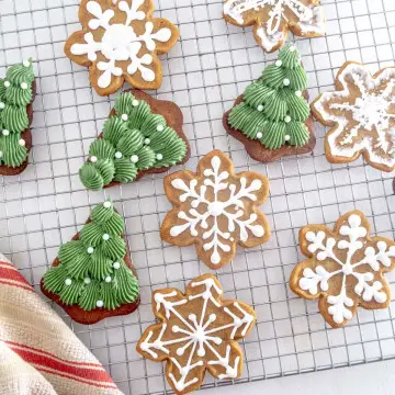 Christmas tree and snow flake vegan gingerbread cookies decorated with vegan royal icing on a wire drying rack