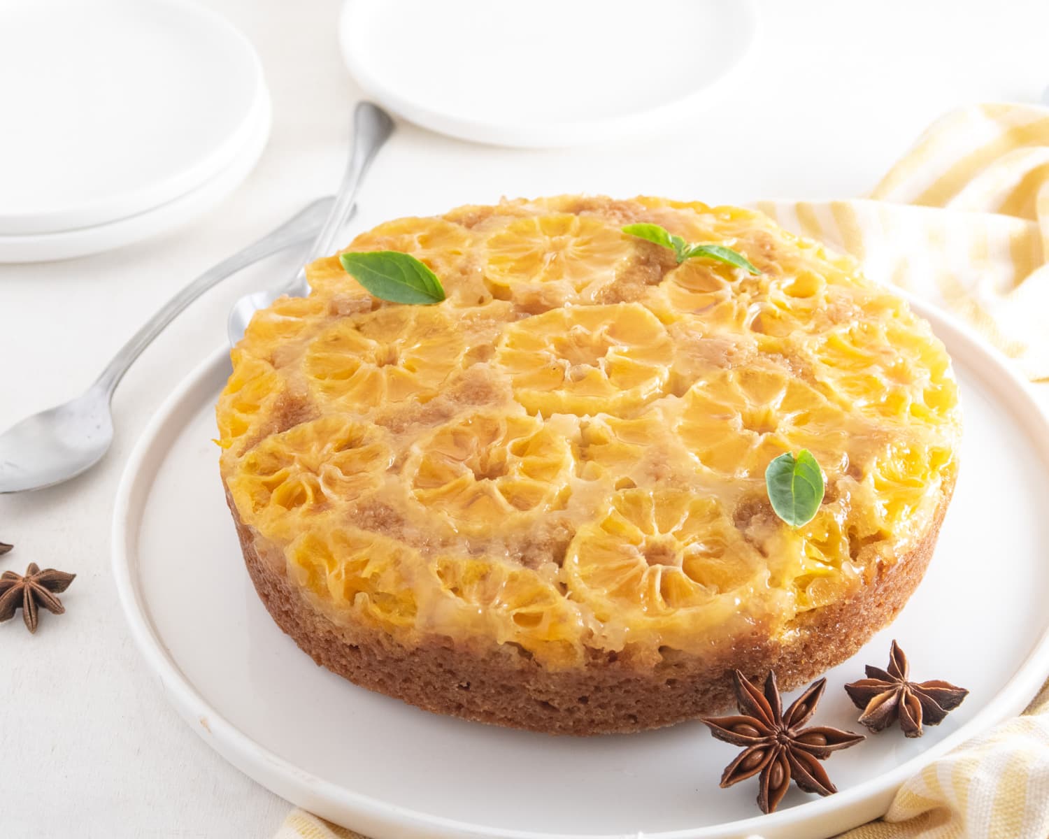 clementine upside down cake in a white plate with star anise and mint garnish