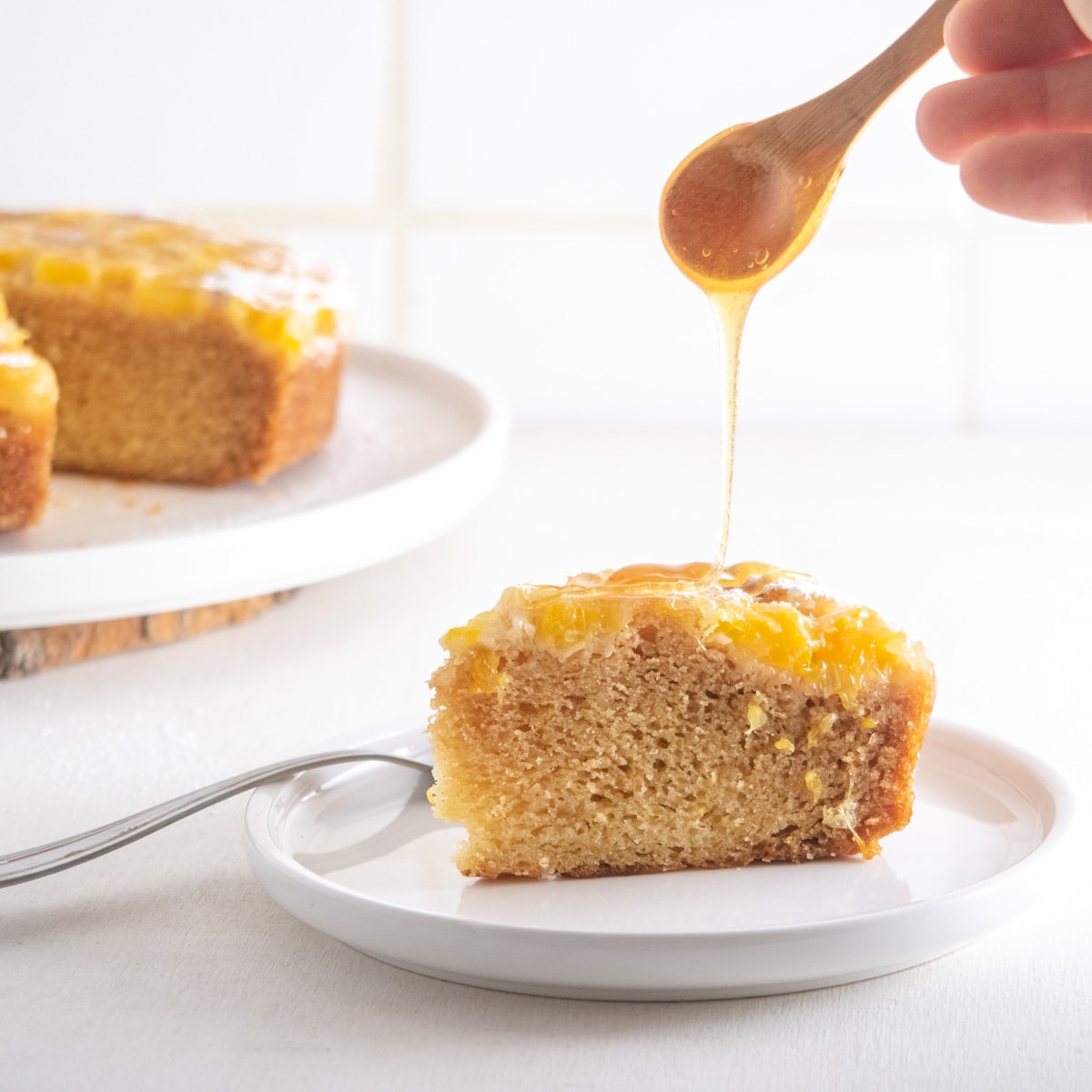 a slice of olive oil and aperitivo cake being drizzled with vegan honey