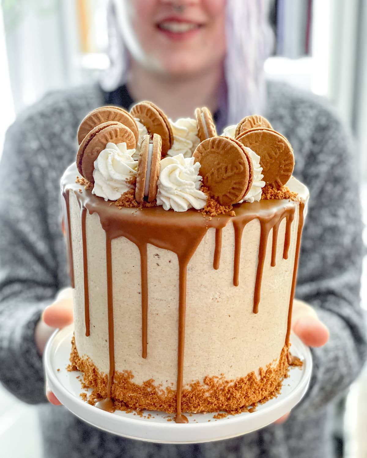 Vegan Speculoos drip cake being held in front of someone who is blurry.