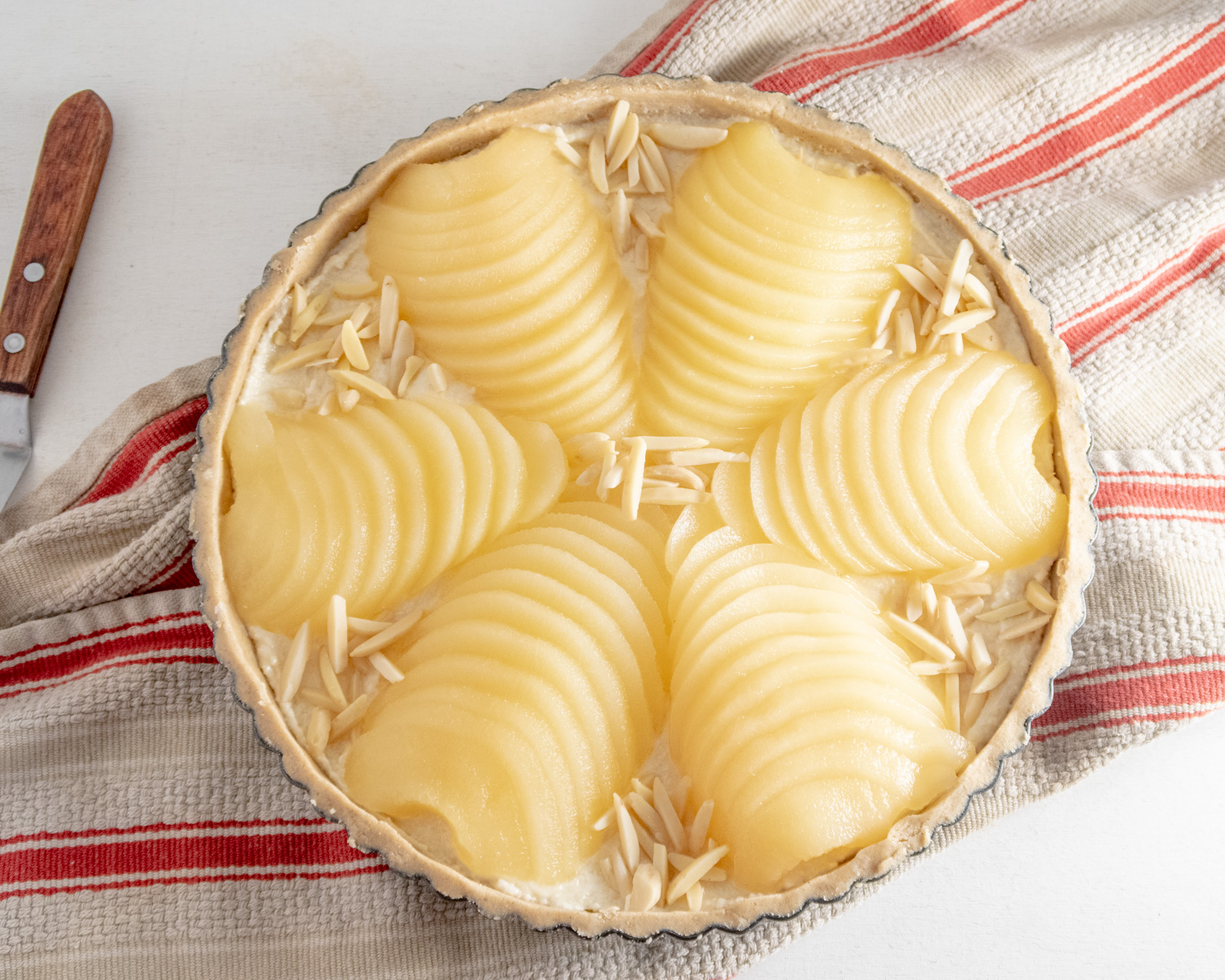 Unbaked Bourdaloue tart on a red-stripped dishtowel.