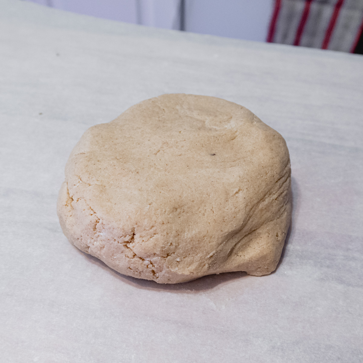 A large ball of gluten-free pâte sucrée dough on a piece of parchment paper.