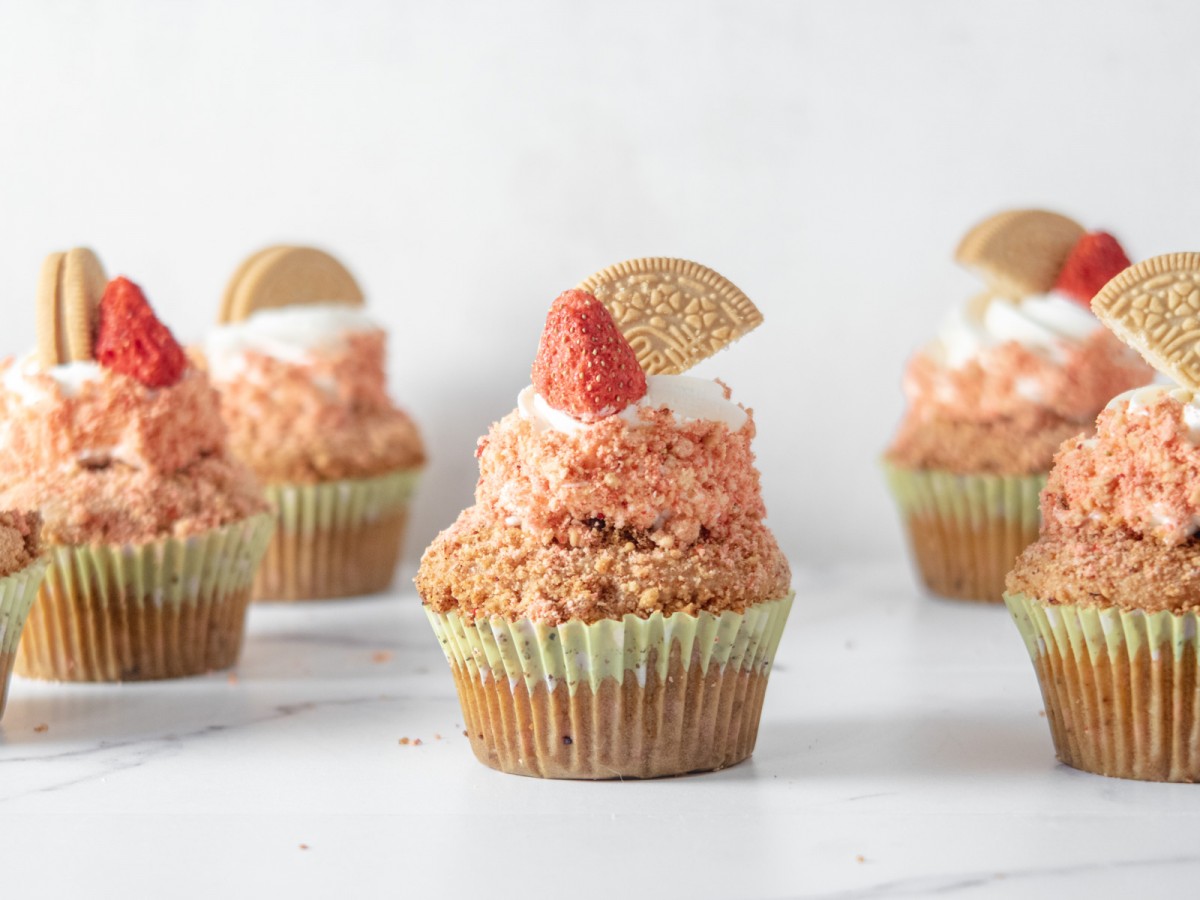 Closeup of a vegan strawberry crunch cupcake in the middle of a cluster of cupcakes that are blurry.