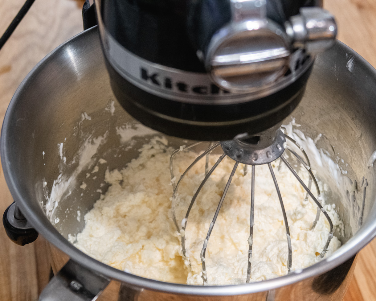 IMBC in a stand mixer bowl at the curdled stage, looking completely split with chunks of butter and clear liquid at the bottom.