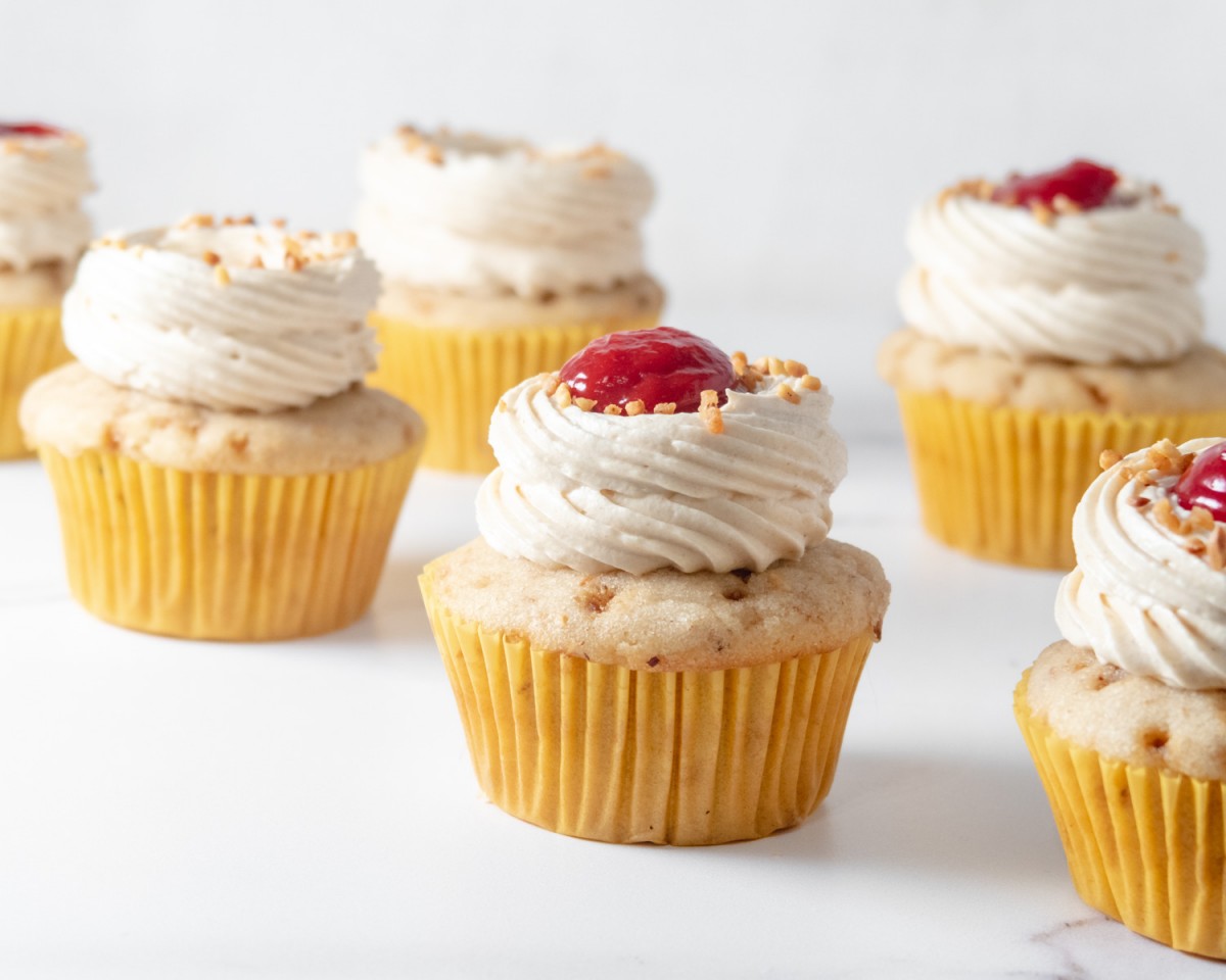 Side view of peanut butter cupcakes, some with raspberry curd on top.