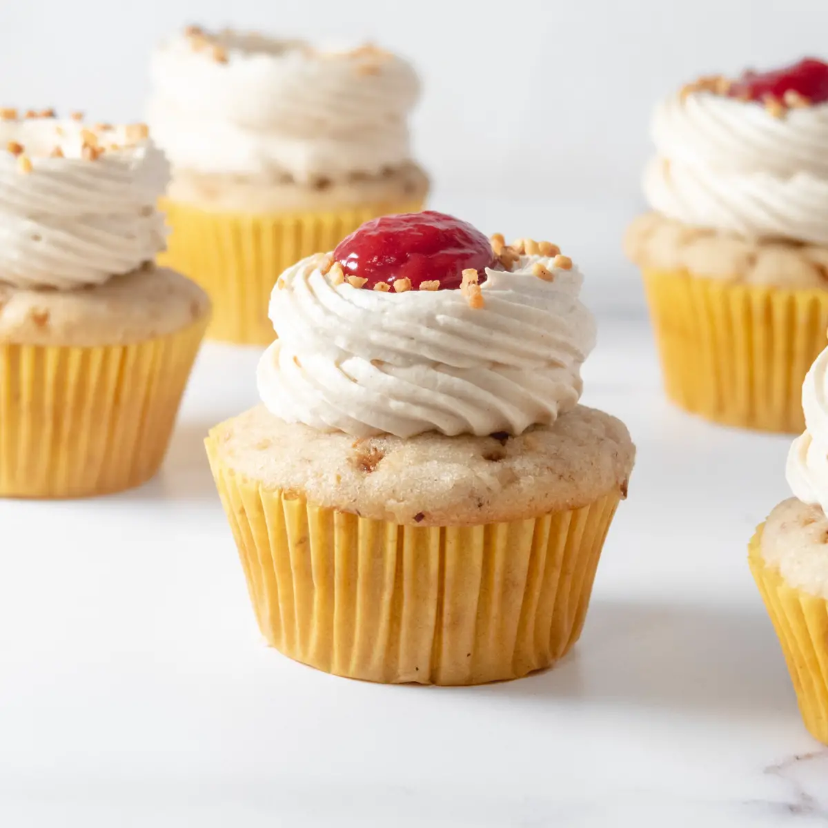 of peanut butter cupcakes, some with raspberry curd on top.