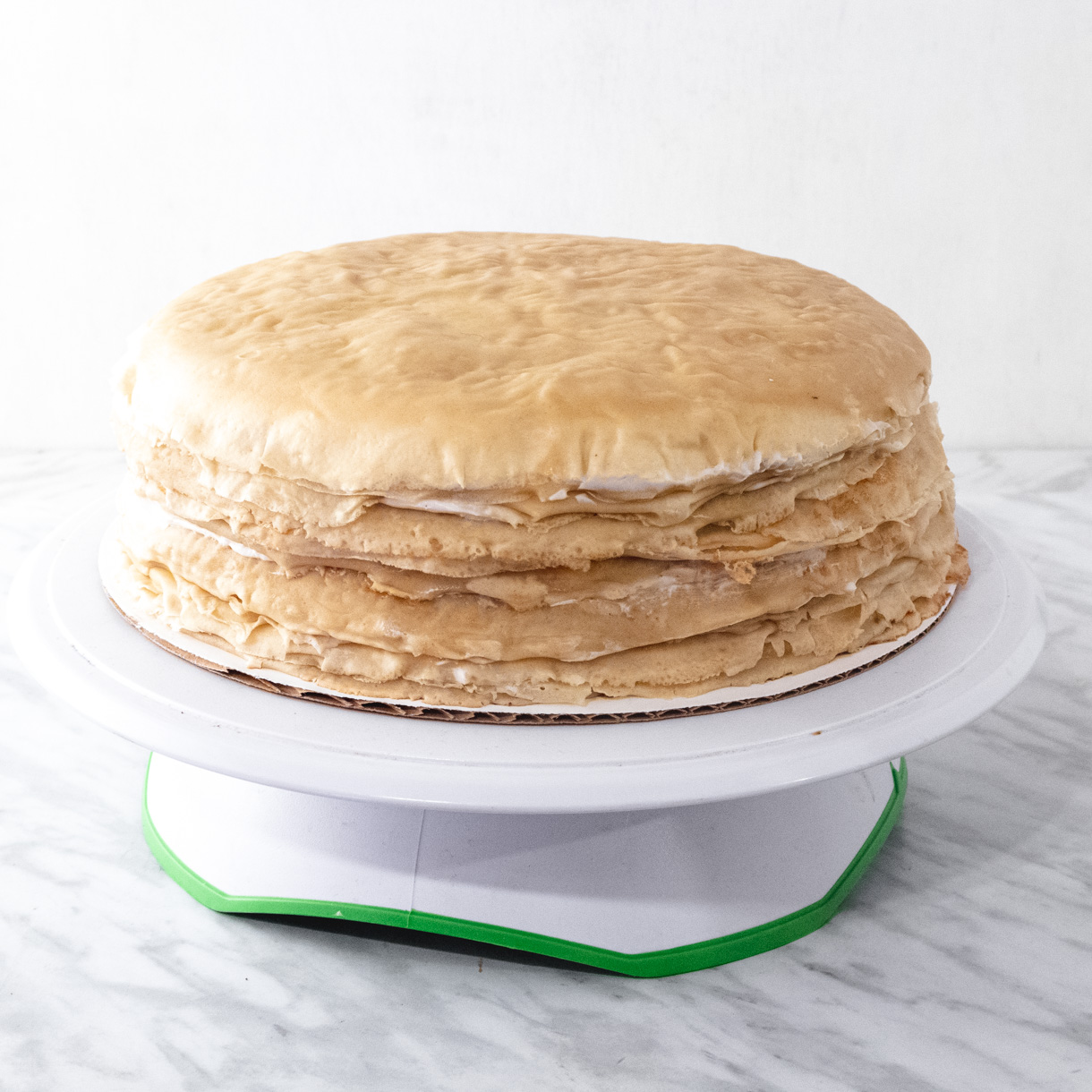 Assembled mille crepe cake on a turntable without the caramelized sugar top.