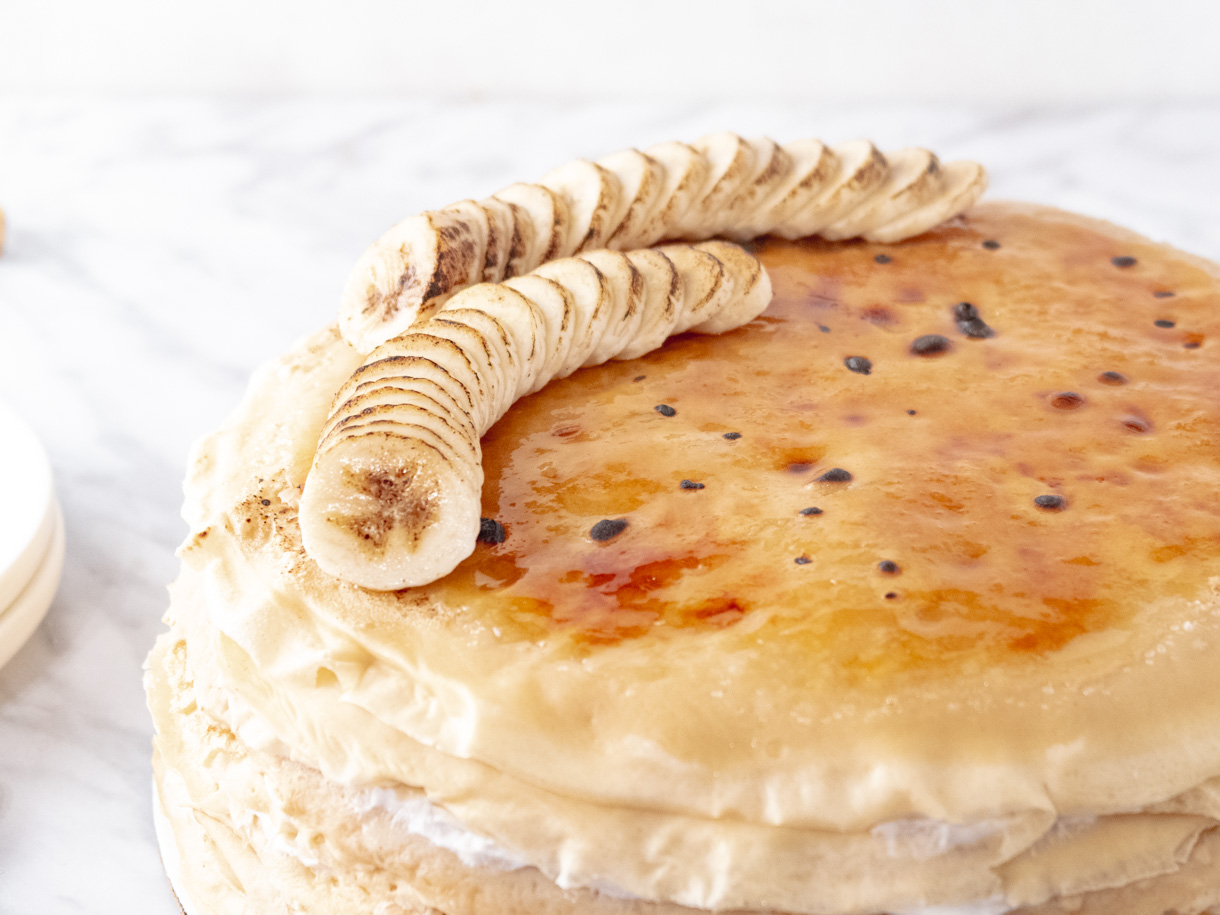 Close up of the torched bananas on top of a vegan mille crepe cake.