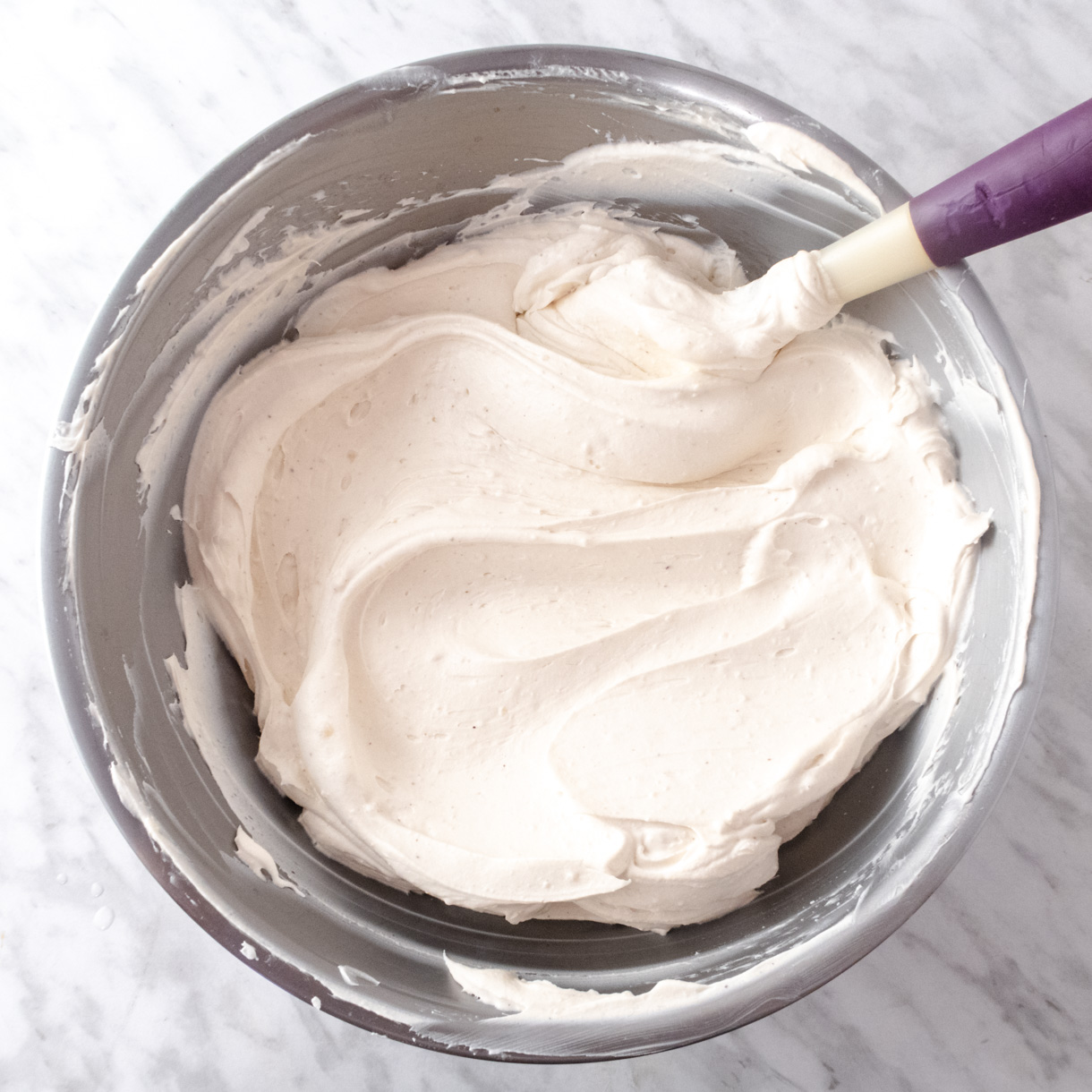 Diplomate cream in a mixing bowl with a silicone spatula.