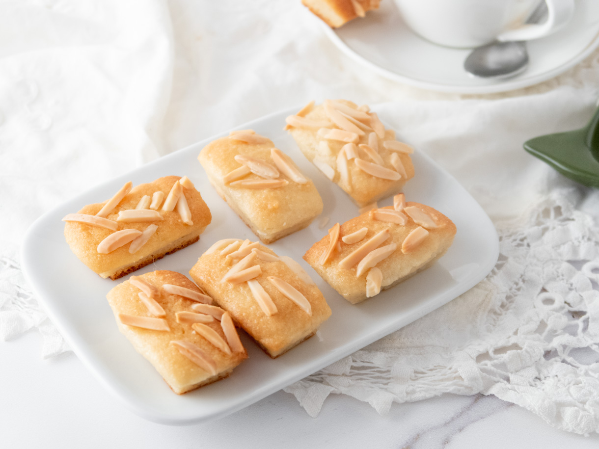 6 financiers placed artfully on a small rectangular white plate on a white background.