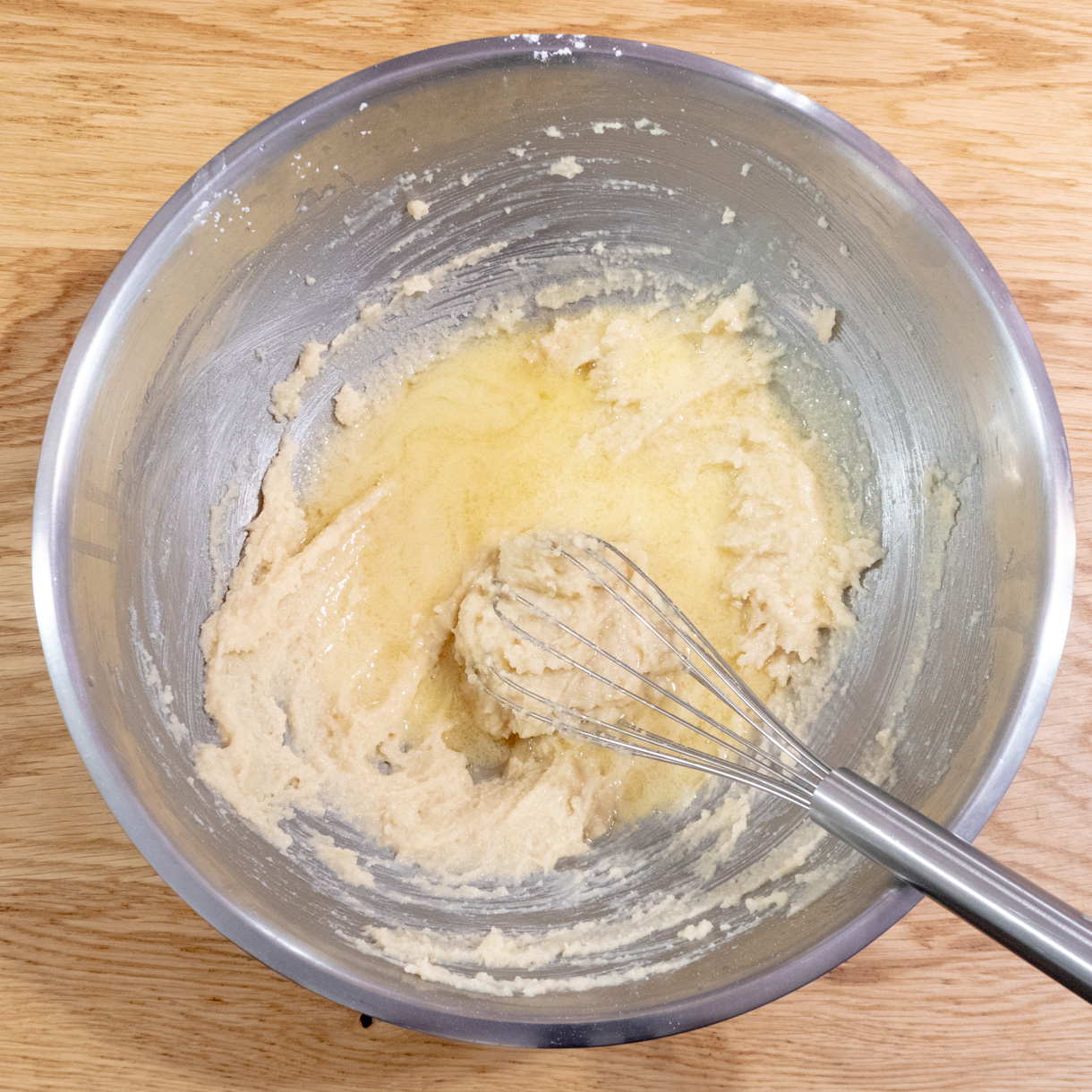 Melted butter, rum and almond extract being mixed into the stiff batter;