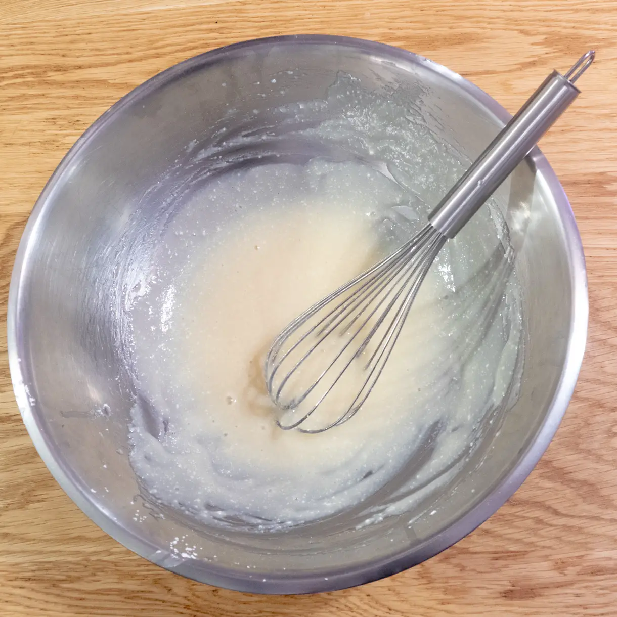 Tofu and powdered sugar whisked together in a large metallic mixing bowl until smooth.