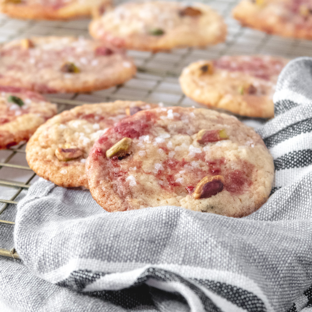 Close up of 2 cookies leaning on each other partly on top of a gray tea towel.