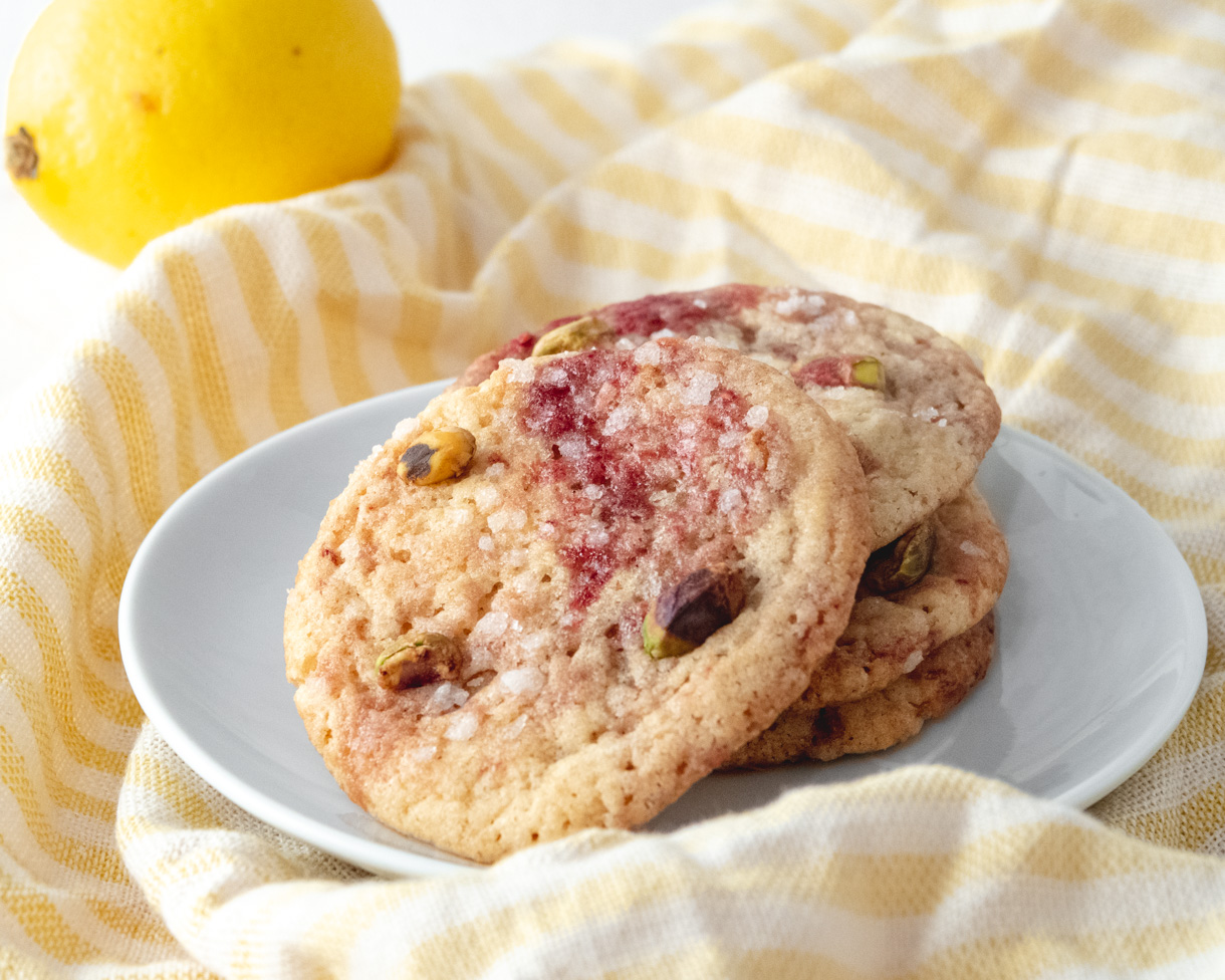 3 cookies on a white plate on top of a yellow striped tea towel.