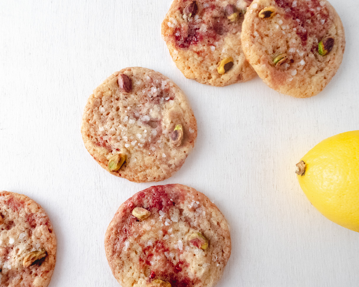 Cookies randobly placed on a white background with a lemon on the right side of the picture.