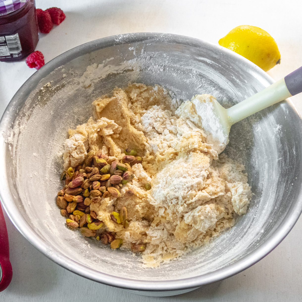 Cookie batter with some dry ingredients still visible with shelled pistachios on one side.