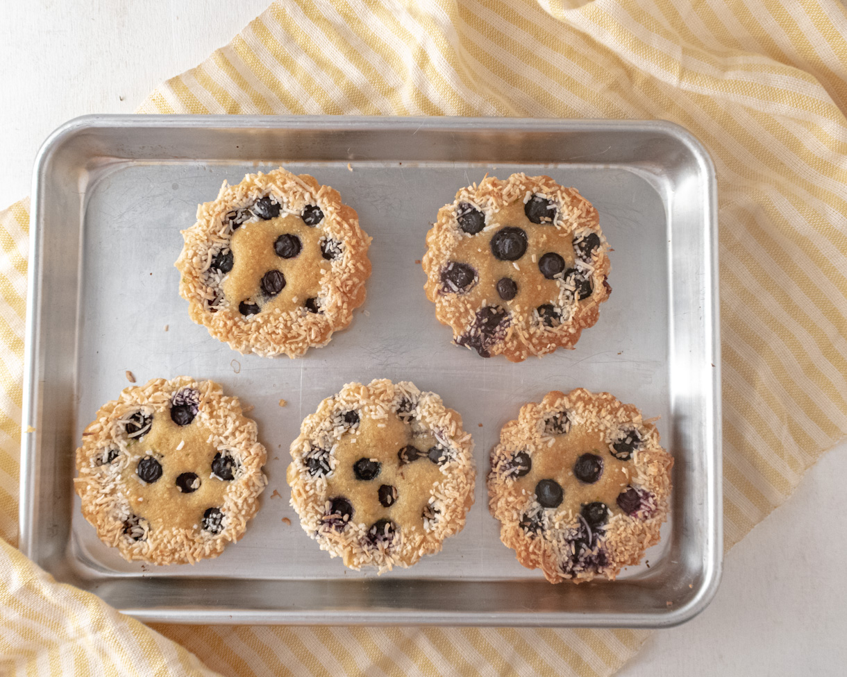 5 financiers on a small baking sheet placed on a yellow stripped teatowel.